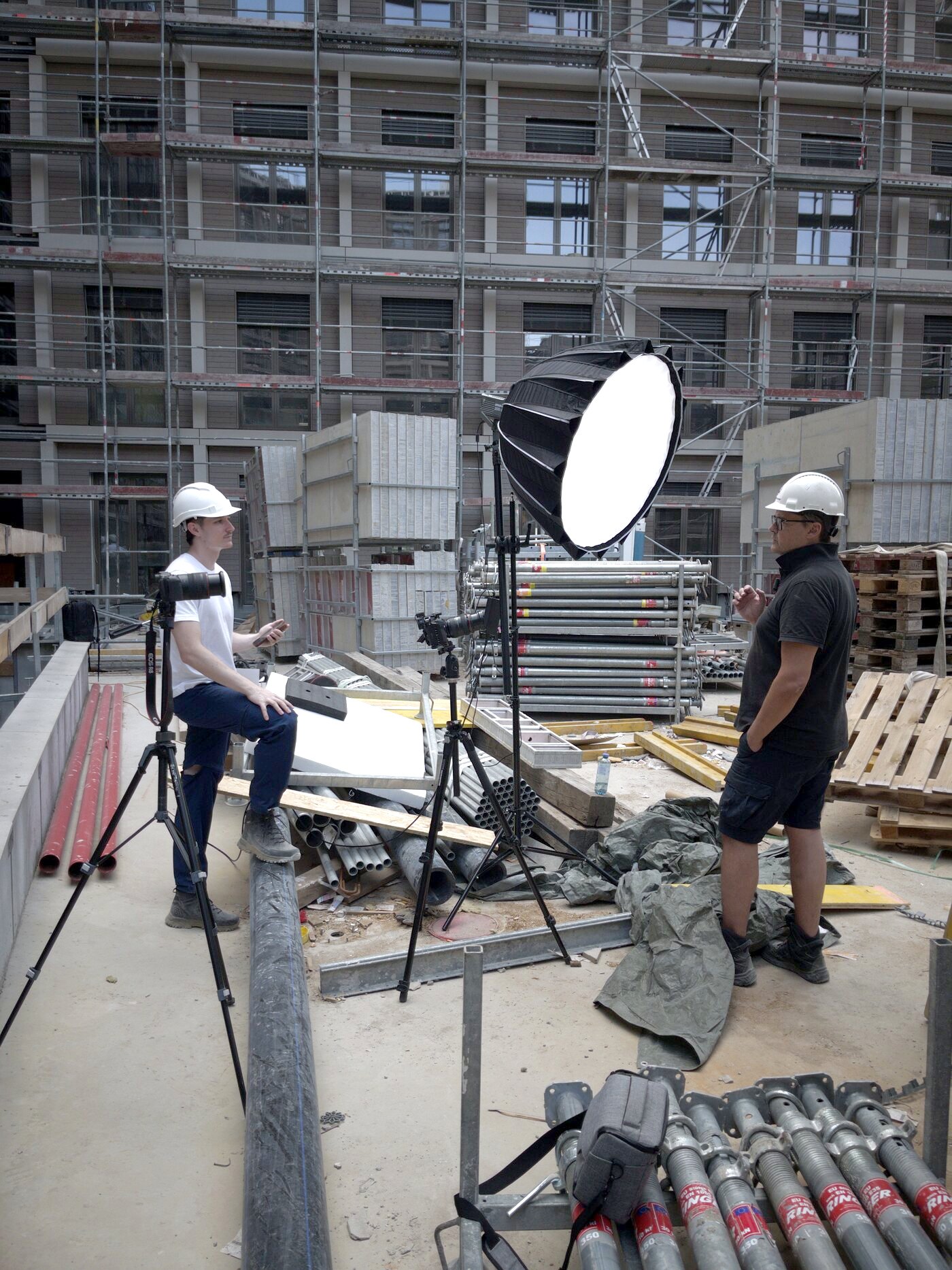 Drehtag auf einer Baustelle, Interview mit Helm vor Gerüst und Schalungsmaterial